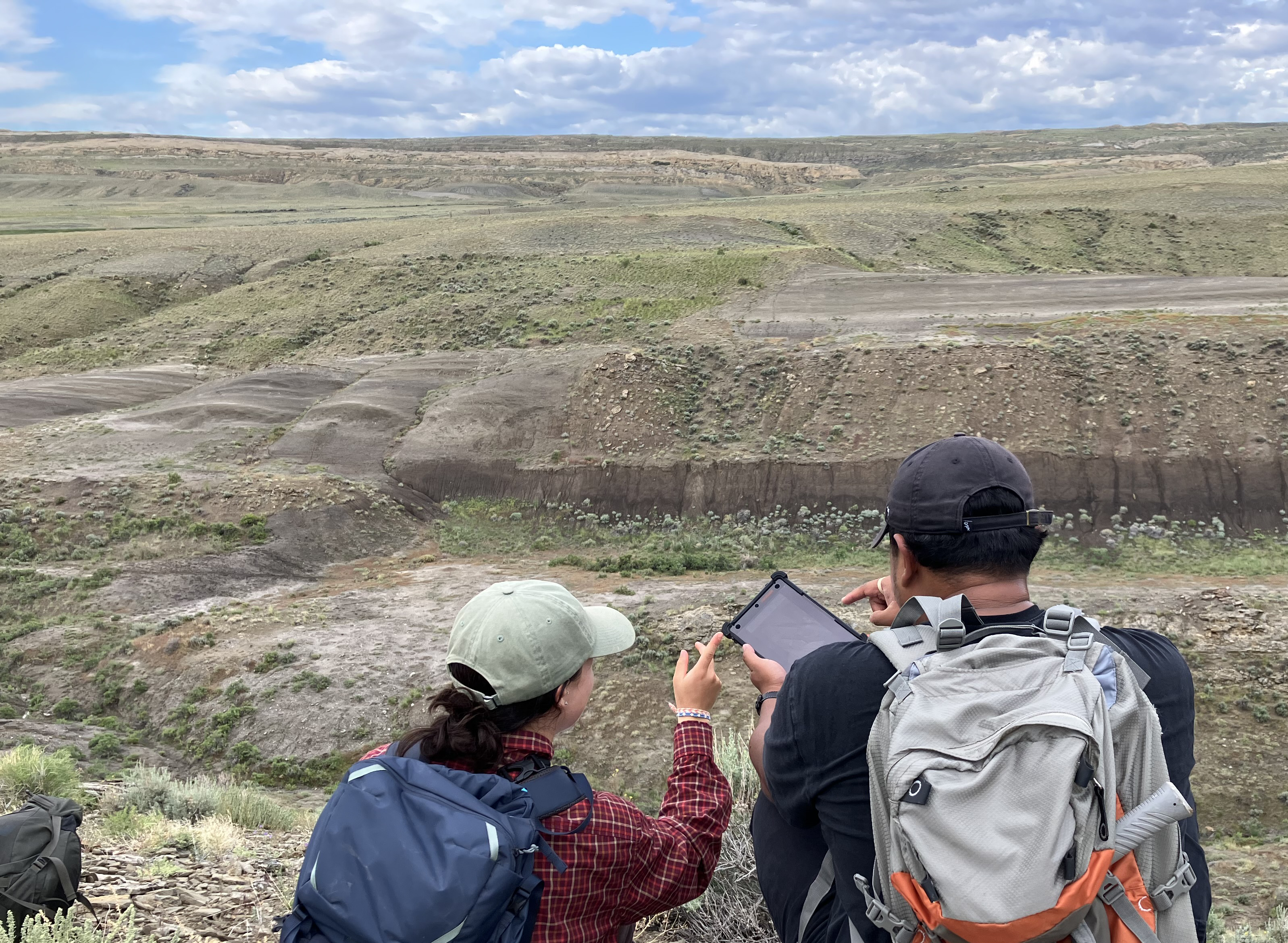 Field camp students compare an outcrop to a digital aerial imagery on a tablet.